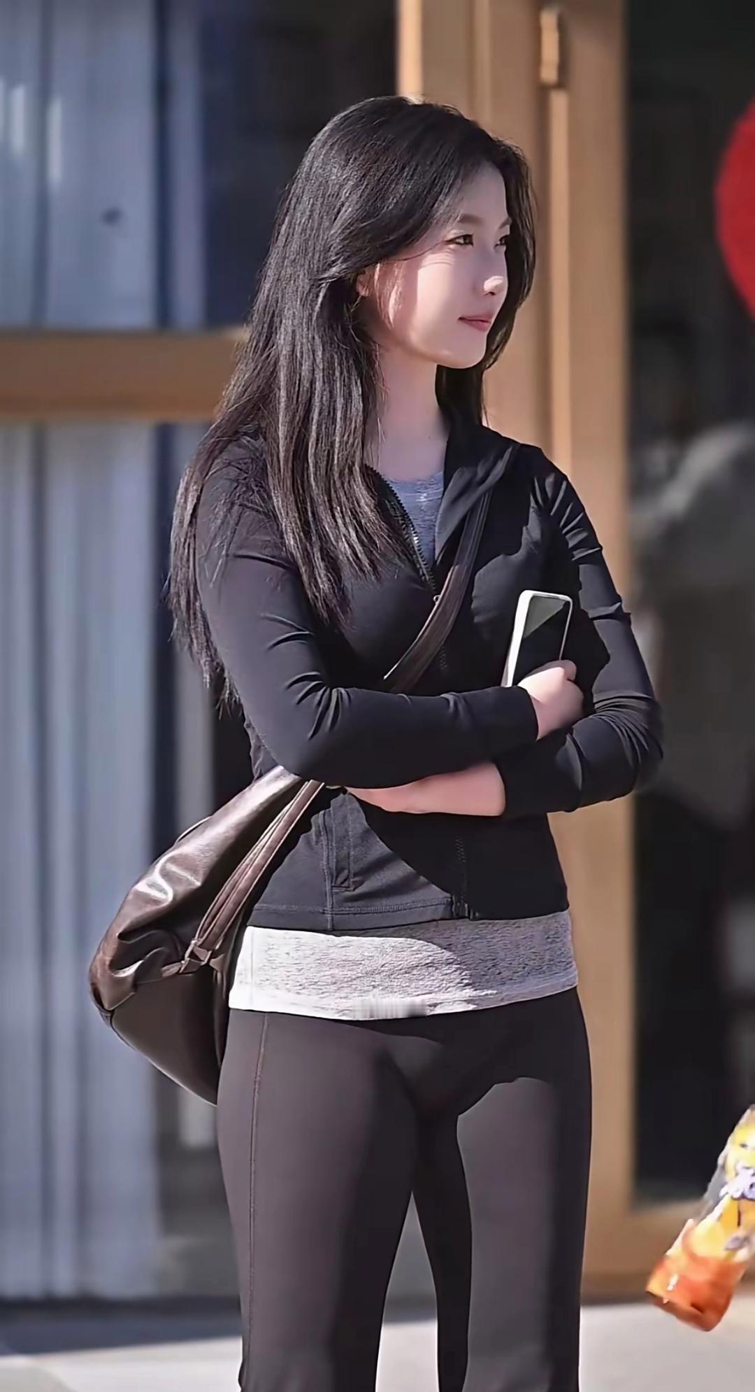 黑衣少女，自信满满，手拿手机，背着大包，走在街头。