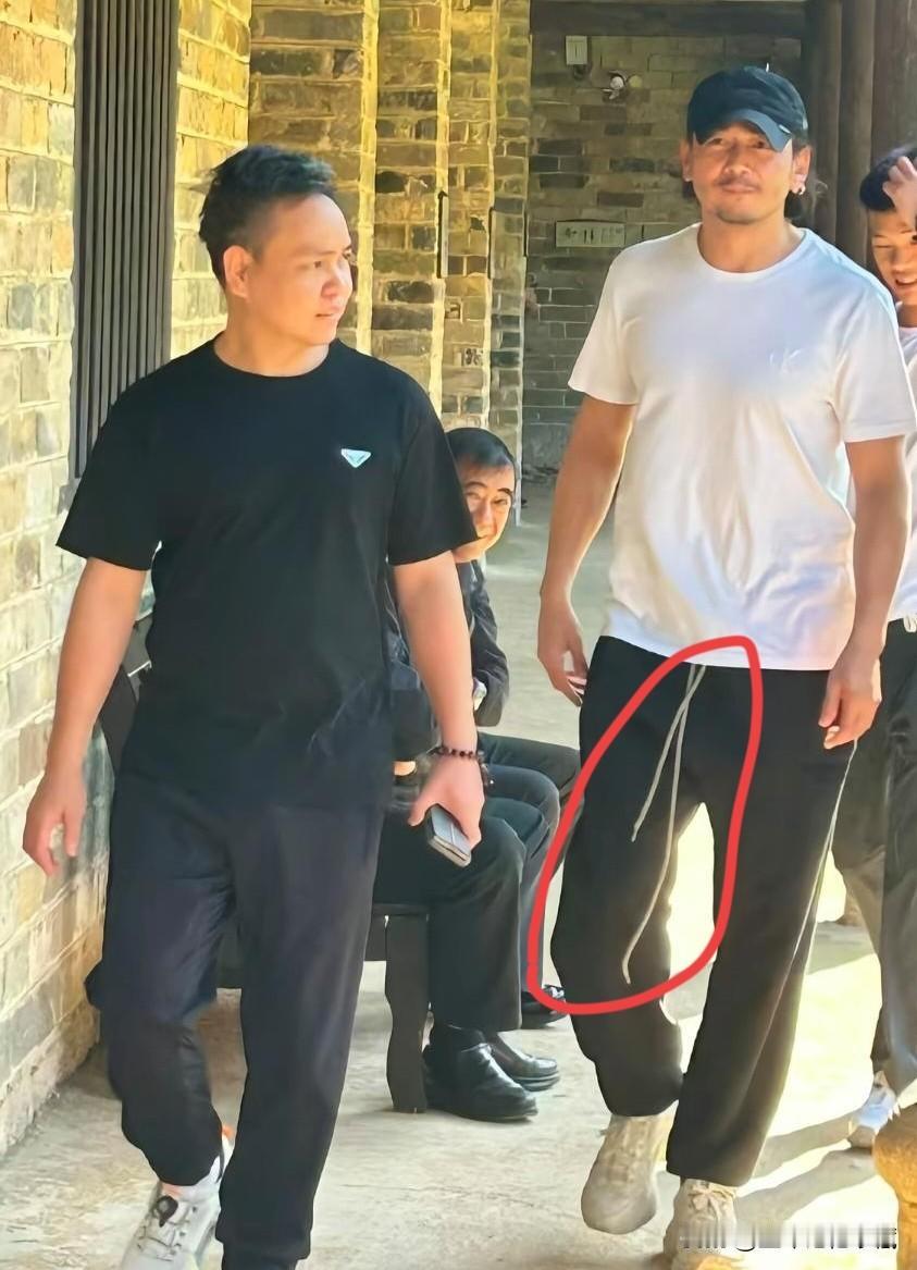 型男杨烁在湖南乡村游玩，头发卷曲，胡子拉碴，身穿白色圆领T恤衫黑色运动裤，裤腰上