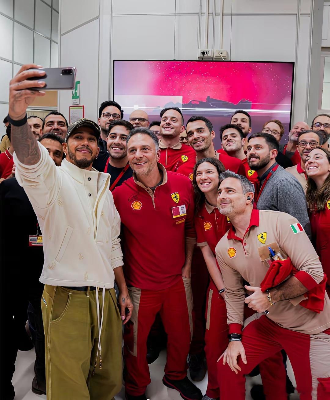 刘易斯·汉密尔顿参观法拉利工厂后，和法拉利员工自拍合影，他手里拿的是哪款手机？