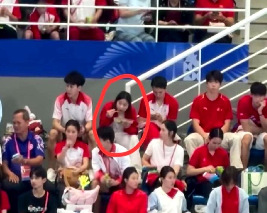 全红婵没上场，却抢了全场镜头。她端着盒饭，蹲在观众席，为队友鼓掌的样子，比夺
