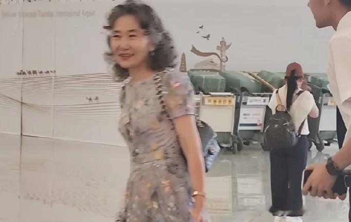望着这位年逾六旬的女士，这份优雅绝非仅仅依靠化妆就能拥有。她左手提包，右手拖着行