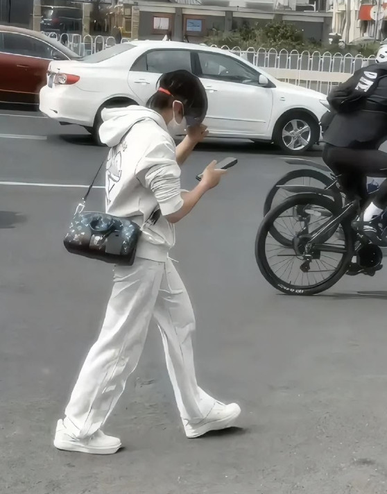 下班路上撞见全红婵了，这穿搭把我看愣了，一身白卫衣白裤子，挎个小包包，低头刷着手