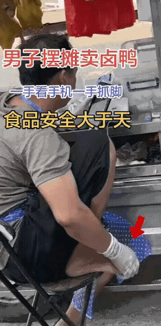 这也太恶心人了男子在卖卤鸭，这时没什么客户，他一手看手机，一手抠脚，手上还戴