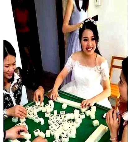 三女一男凑一桌搓麻将，仨女的都穿着短裙红裙子大姐刚摸张牌要打，手机突然震起来