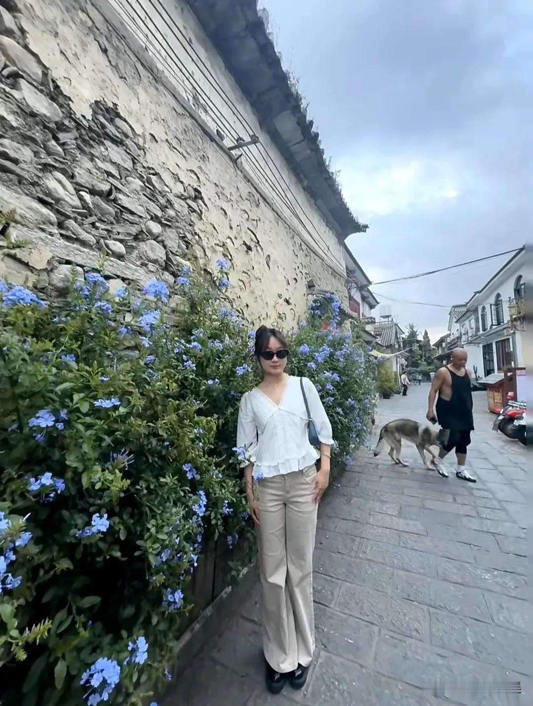 51岁的乐嘉在大理街头遛狗，留着标志性的光头，穿着一件黑色的宽松吊带背心，搭配五