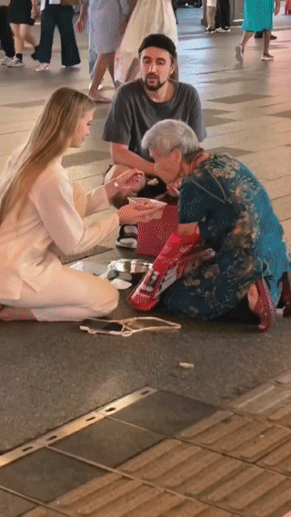一对外国情侣在街头看到一名流浪乞讨的老奶奶十分的可怜！于是他们就走上前想帮一下
