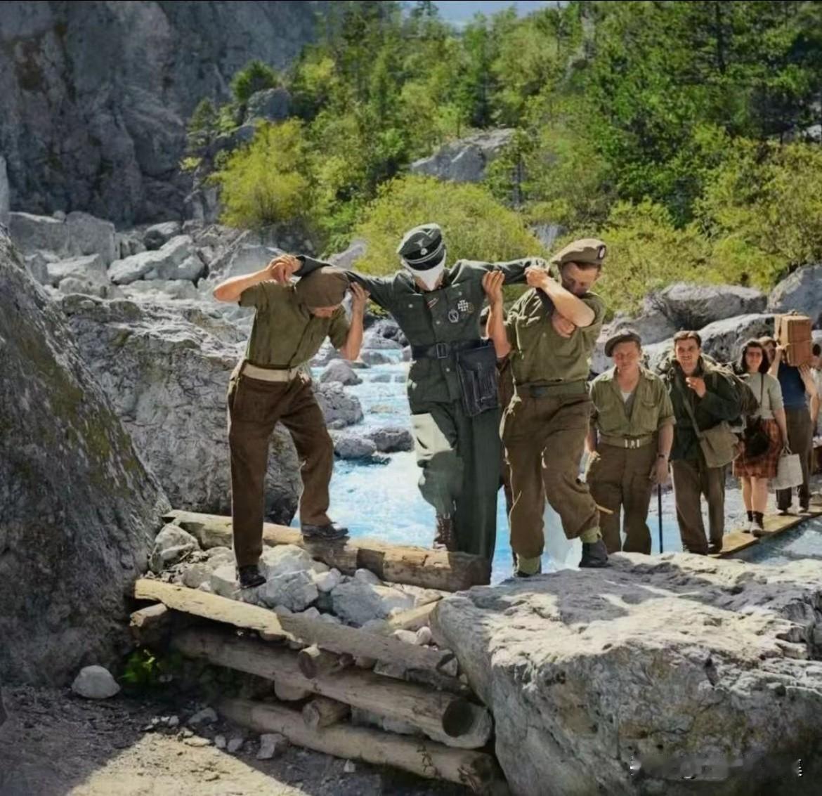 1945年5月7日，意大利塔维西奥英军防线前，两名英国士兵押送一名被蒙住眼睛的德