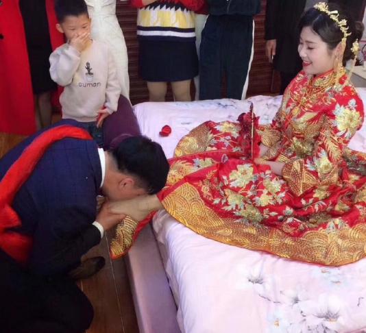 婚礼上新郎深情款款亲新娘的脚，全场宾客都在拍手起哄，大喊“亲一个！再来一个！”