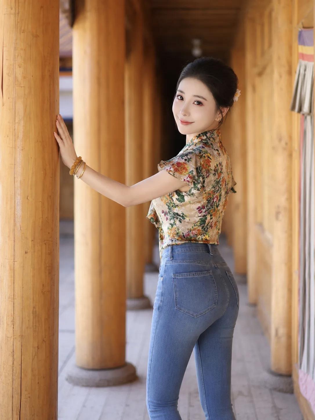 一位女生在廊道里靠柱摆姿势。