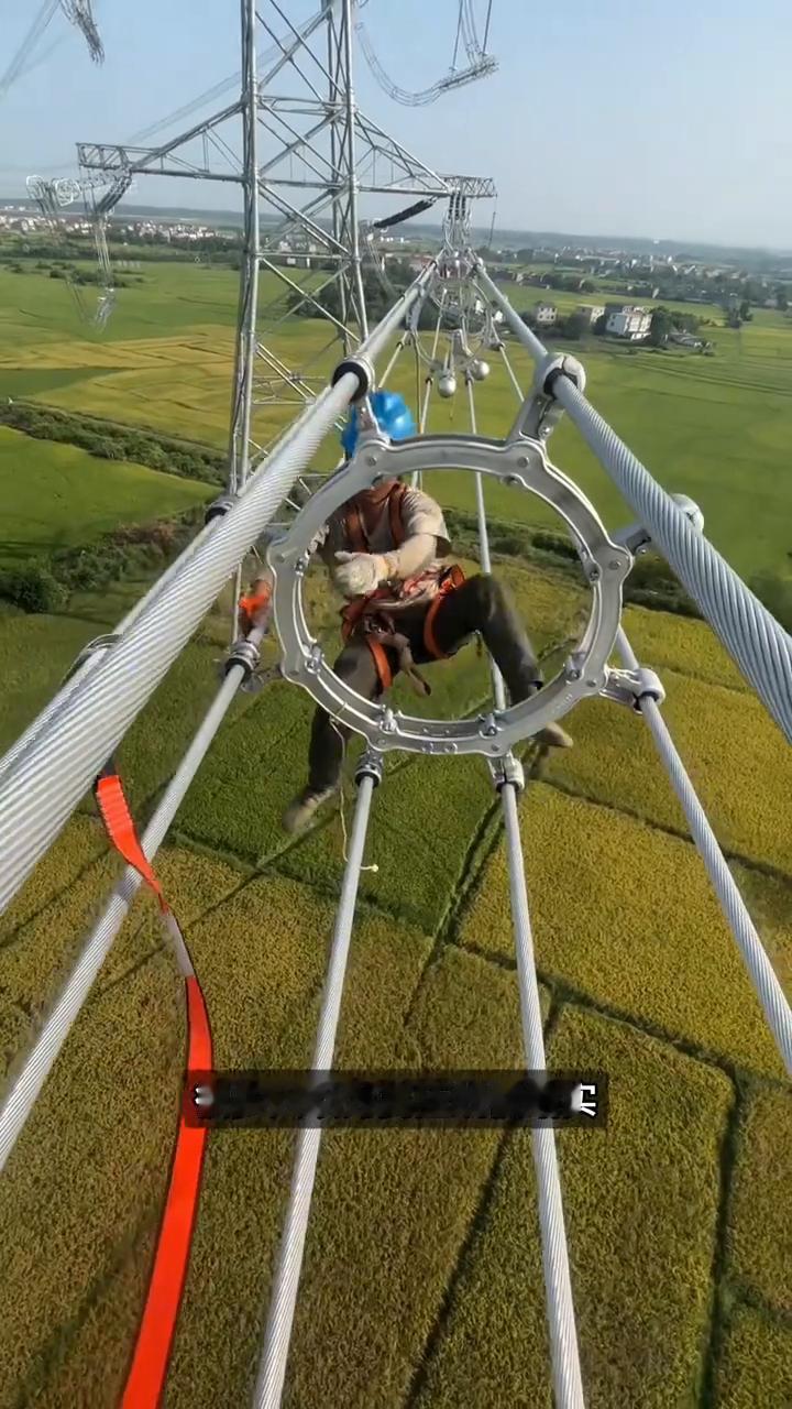 电线的防震锤。注意看，这根电线还在疯狂抽动，工人往上一挂，这个哑铃下一秒直接不