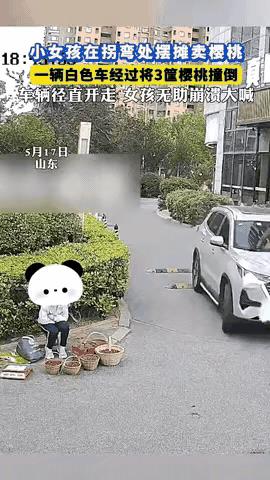 青岛某小区门口，小女孩提着三篮樱桃在门口售卖，一辆白色的越野车经过直接从樱桃上面