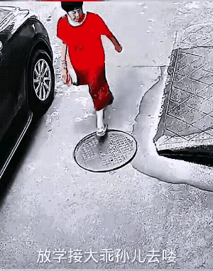 这才是中国大妈该有的形象。马路上，着红色衣裙的大妈一脚踏上松动的窨井盖，差点掉
