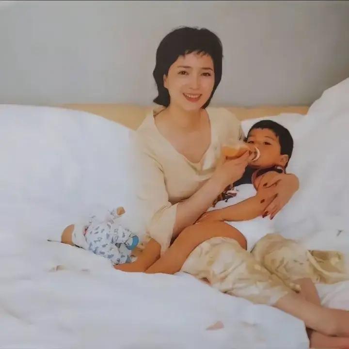 这是2001年，演员何晴与襁褓中的儿子幸福温馨的合影，何晴穿着卡其色真丝面料套装