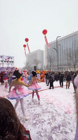 山西太原一个商场开业。现场的美女歌舞团的女演员竟然穿着单薄的衣服冒着大雪跳舞。
