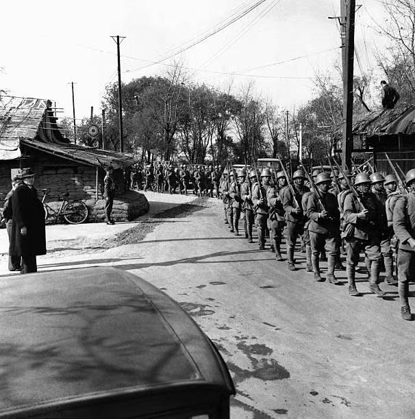 图一：1937年，淞沪会战期间，日寇士兵正列队行进在街头。看周边有租界士兵警戒