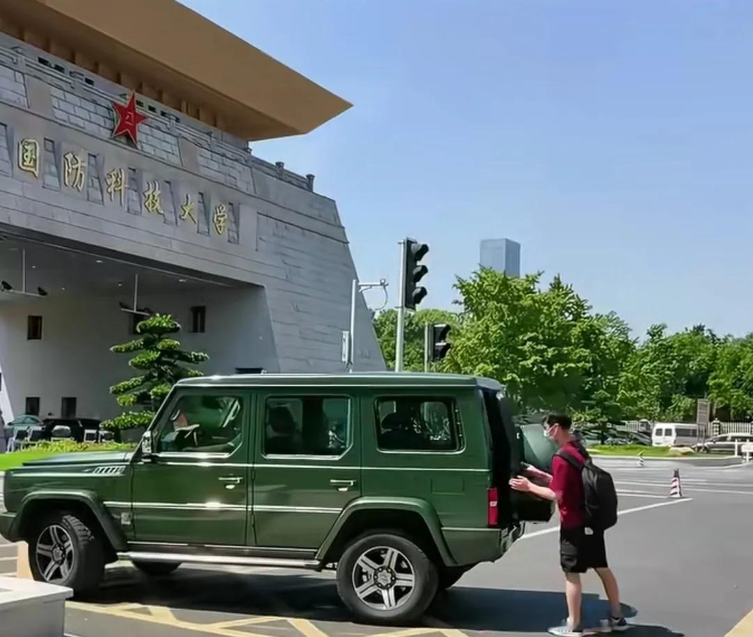 国防科技大学门口一辆绿车送学生到大门口。