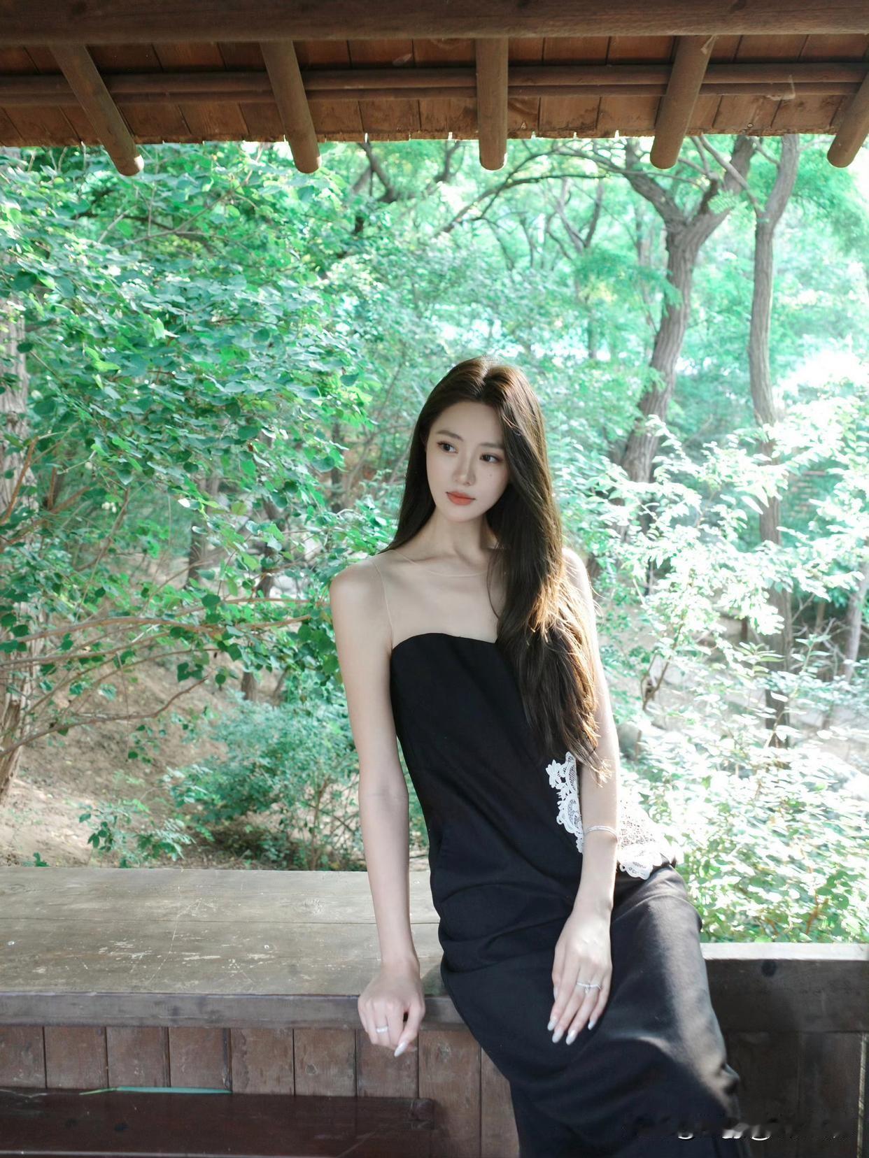 黑裙少女，静坐木桌旁，绿意盎然中，感受自然的宁静与美好。