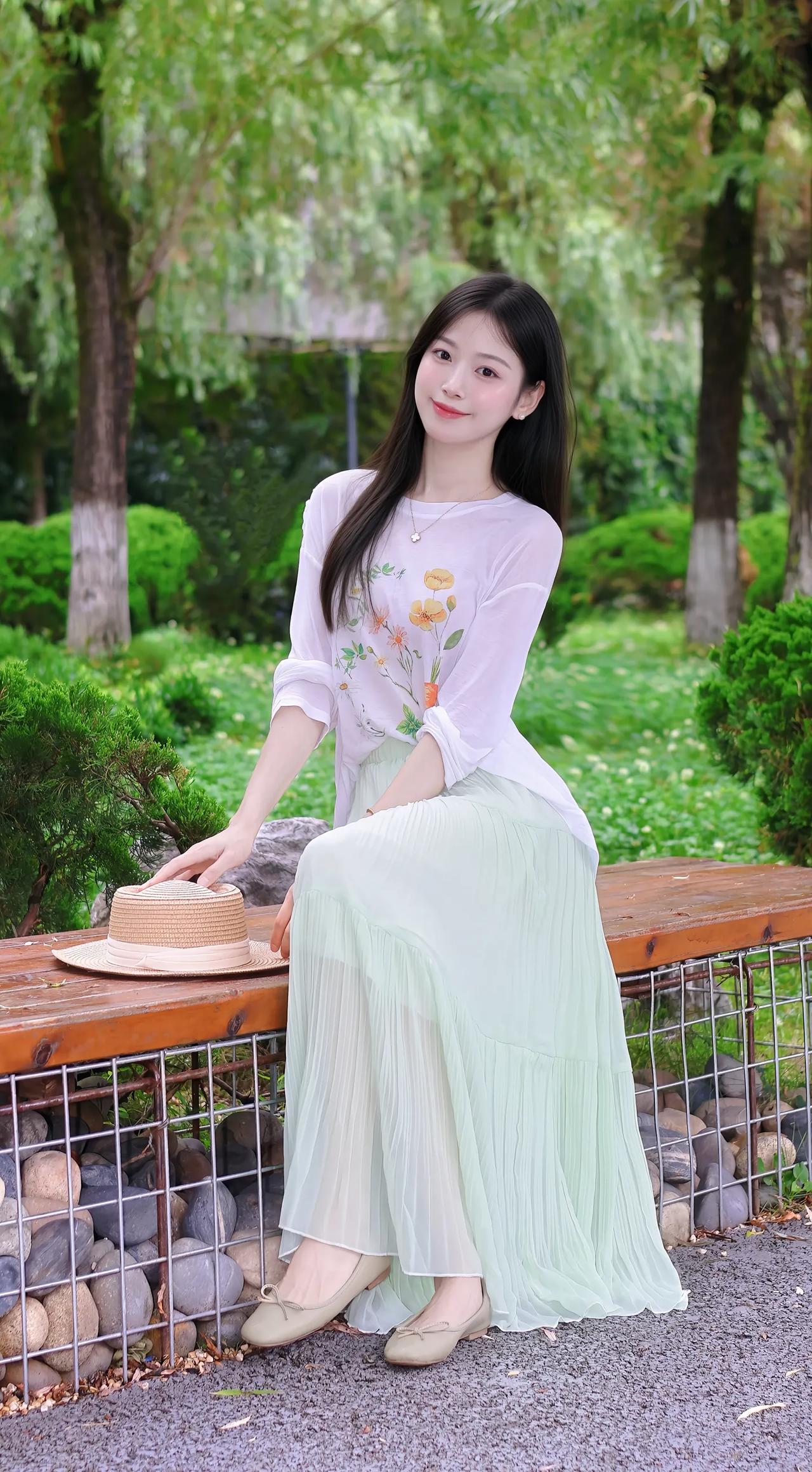 绿衣美人倚长凳，花影摇曳映春光。