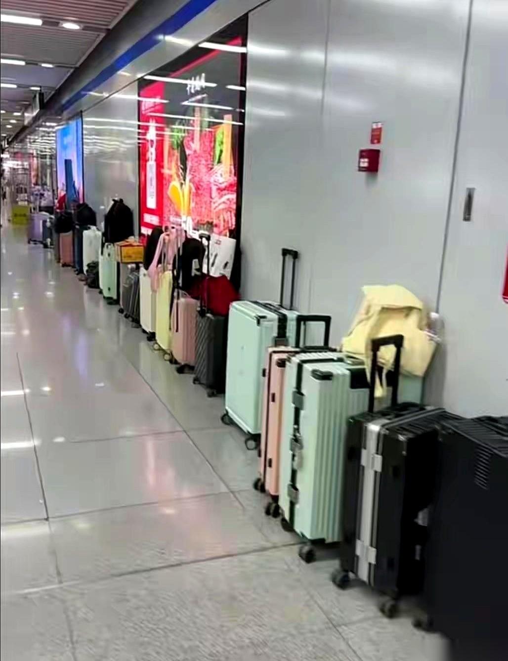 安徽合肥南站，五一，人挤人。一个大学生模样的男孩，把一个大行李箱孤零零地往大通道