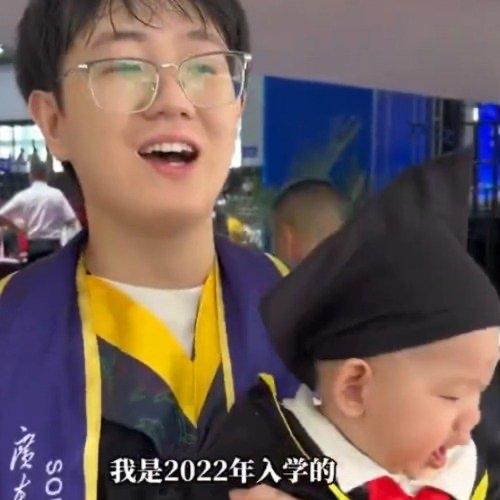 广外南国的毕业典礼上，一个24岁的男毕业生抱着未满一岁的儿子上台拨穗，瞬间在网上