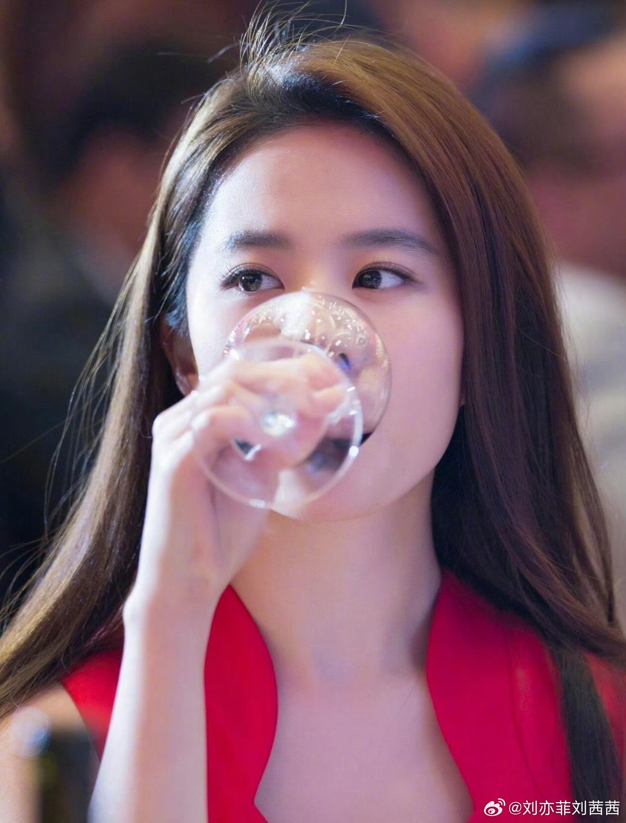 刘亦菲身着一袭正红色无袖修身裙装，利落的剪裁凸显出她优雅的肩颈线条，简约的V领设