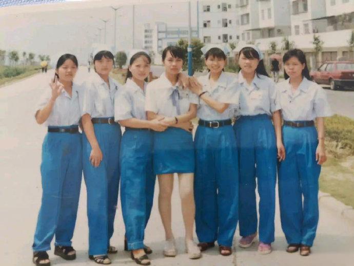 1996年的广东东莞厚街，一家电子厂的厂房外，七个打工妹的合影。这七个姑娘都是