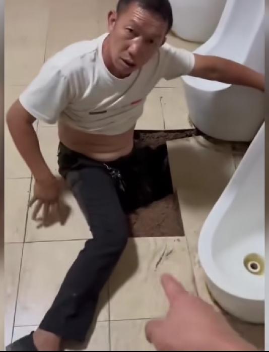 大哥只想上个厕所，没想到刚站那里，便池旁边的地板砖塌陷，一条腿都卡住了。看大哥