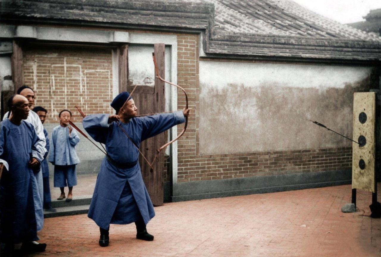1871年，福建福州琴江三江口水师旗营大门前，一名八旗兵正在向苏格兰摄影家约翰・