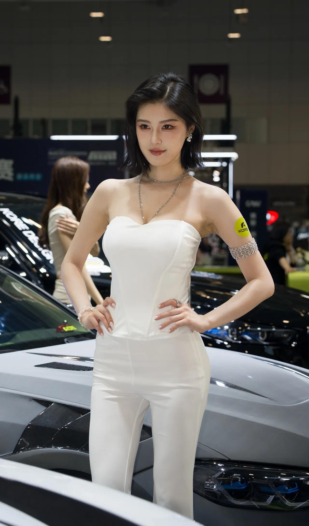 车展上，优雅车模程儿身着白色礼服惊艳亮相，与豪车相映成辉。2026年5月27日，