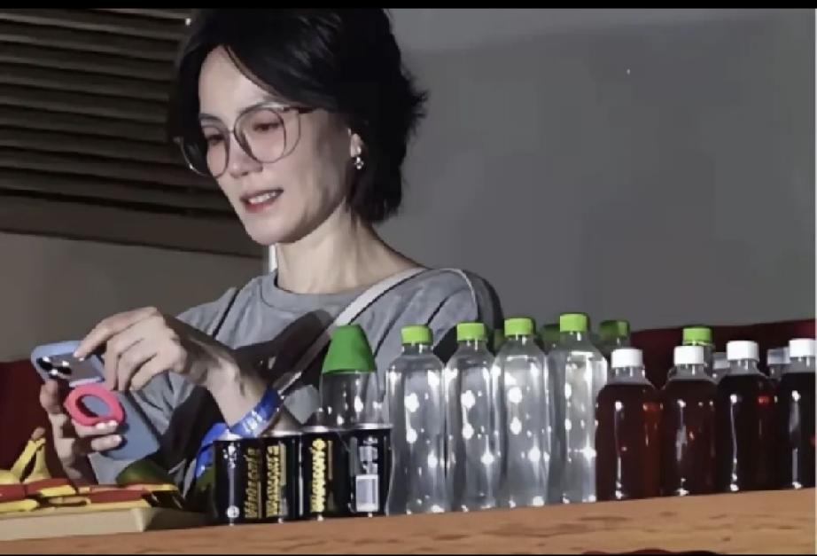 那英演唱会包间里的王菲，正在饶有兴趣的看手机里的内容。摆放在她面前的瓶装水都没