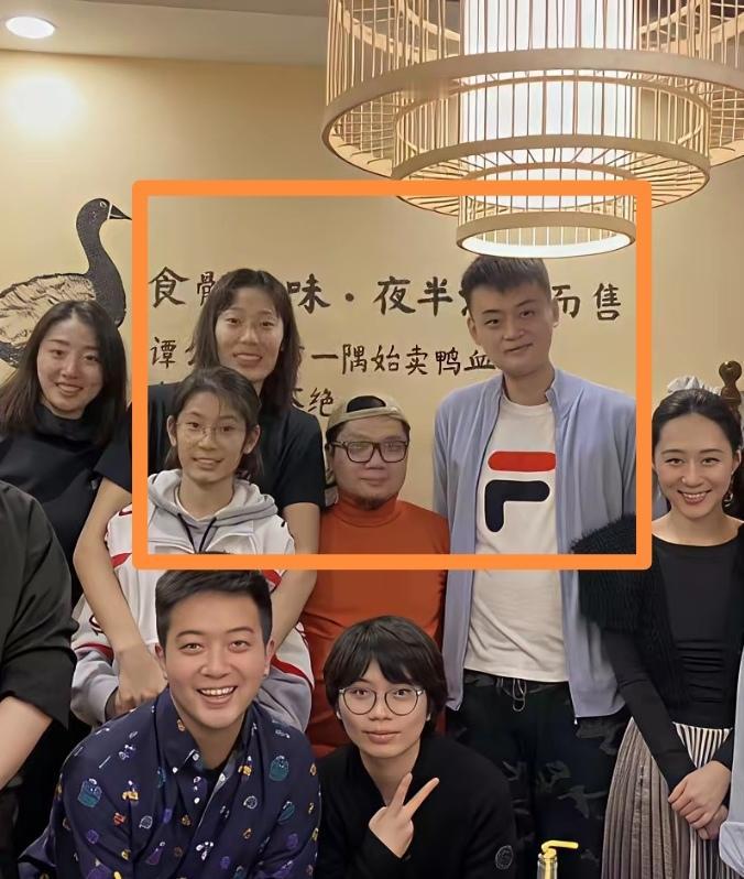 程青松这张合影照片，他到底是和众多朋友一起站着合影呢？还是他在后面单独坐着合影？
