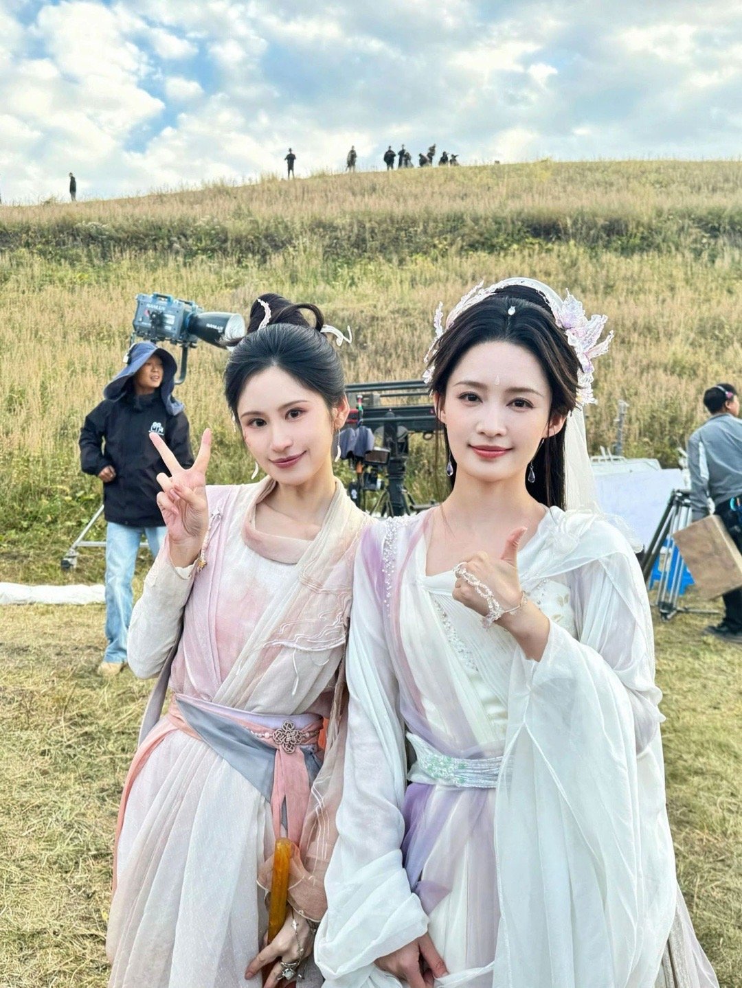 李沁片场同框也太仙了吧！李沁一袭白紫渐变仙裙，搭配精致头饰，温婉大气；身旁的伙