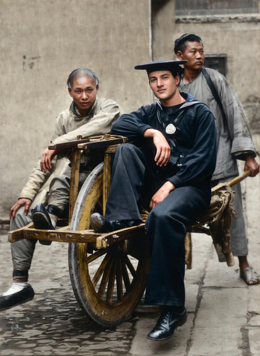 清朝，北京街头，一位外国水兵端坐车上，一位清朝男子在一侧坐着协助维持平衡，照片中