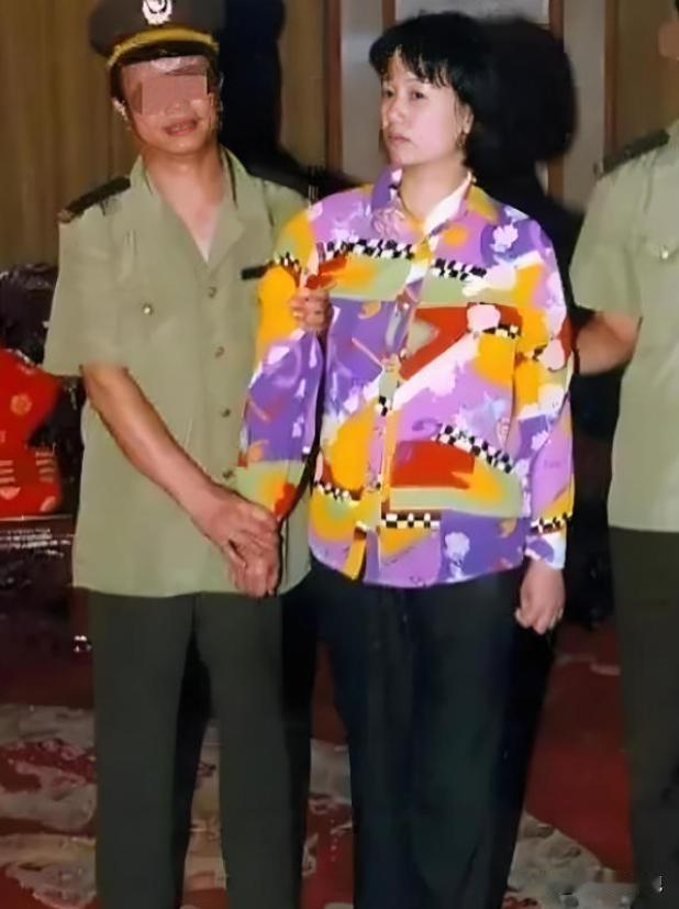 2000年，刘艺霞被判死刑，照片中的她，身穿花衬衫，被两名警察押送着，面无表情，