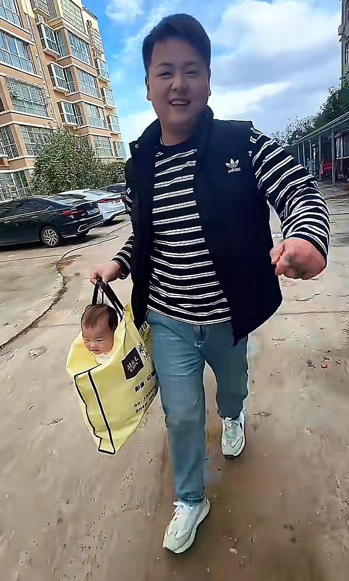 心太大！10月13日河南，一位爸爸为哄娃将孩子塞进购物袋提着走。宝妈在一旁拍视频