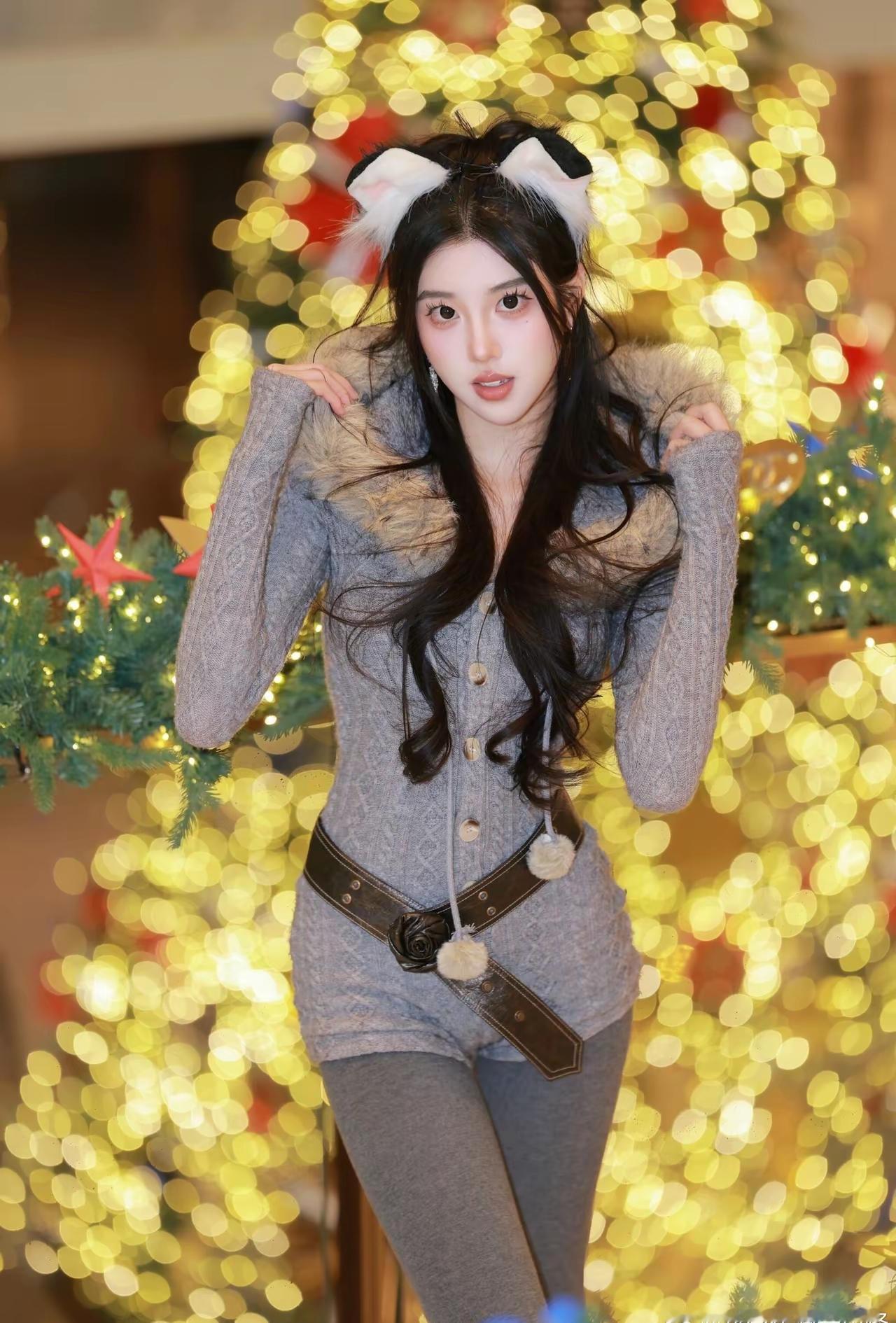 穿猫耳装饰的可爱女孩在圣诞树前摆姿势。