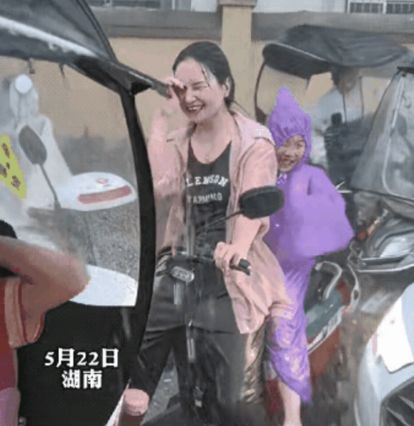 5月22日，湖南，老天突降暴雨，去接女儿放学的妈妈把唯一的一件雨衣披在了女儿身上