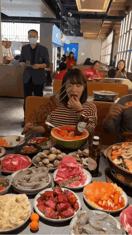 情侣来餐厅吃自助餐，拿了很多的东西，女孩和男友边吃边唠，餐桌上堆满了大虾、肥牛、