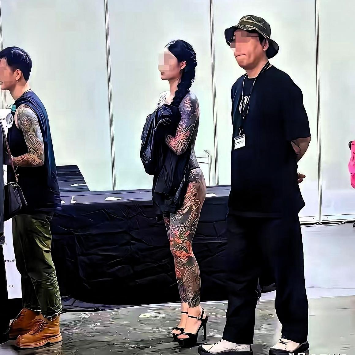 看横幅上写着“纹身艺术节”。男男女女纹身爱好者们带着“皮肤艺术”粉墨登场。中间这