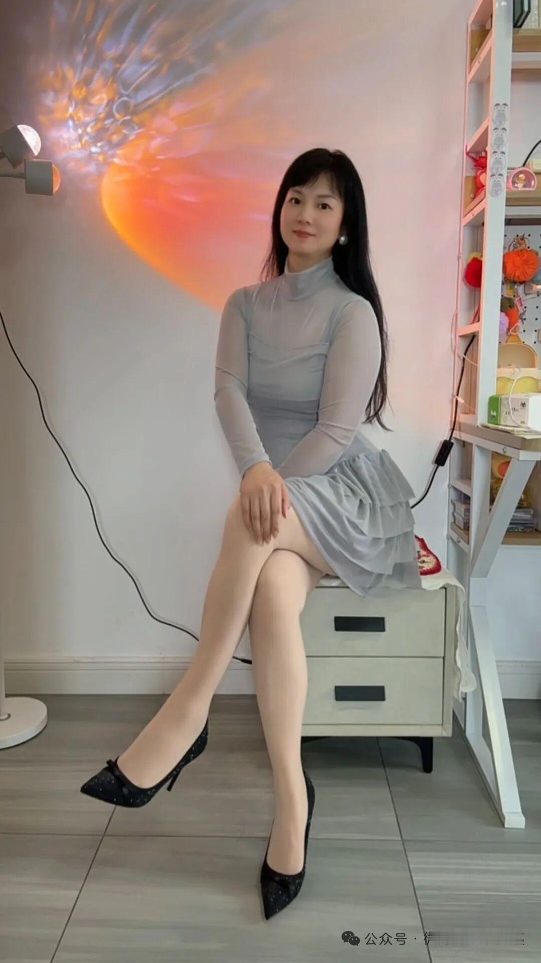 她坐在椅子上，穿着裙子，脚穿高跟鞋。