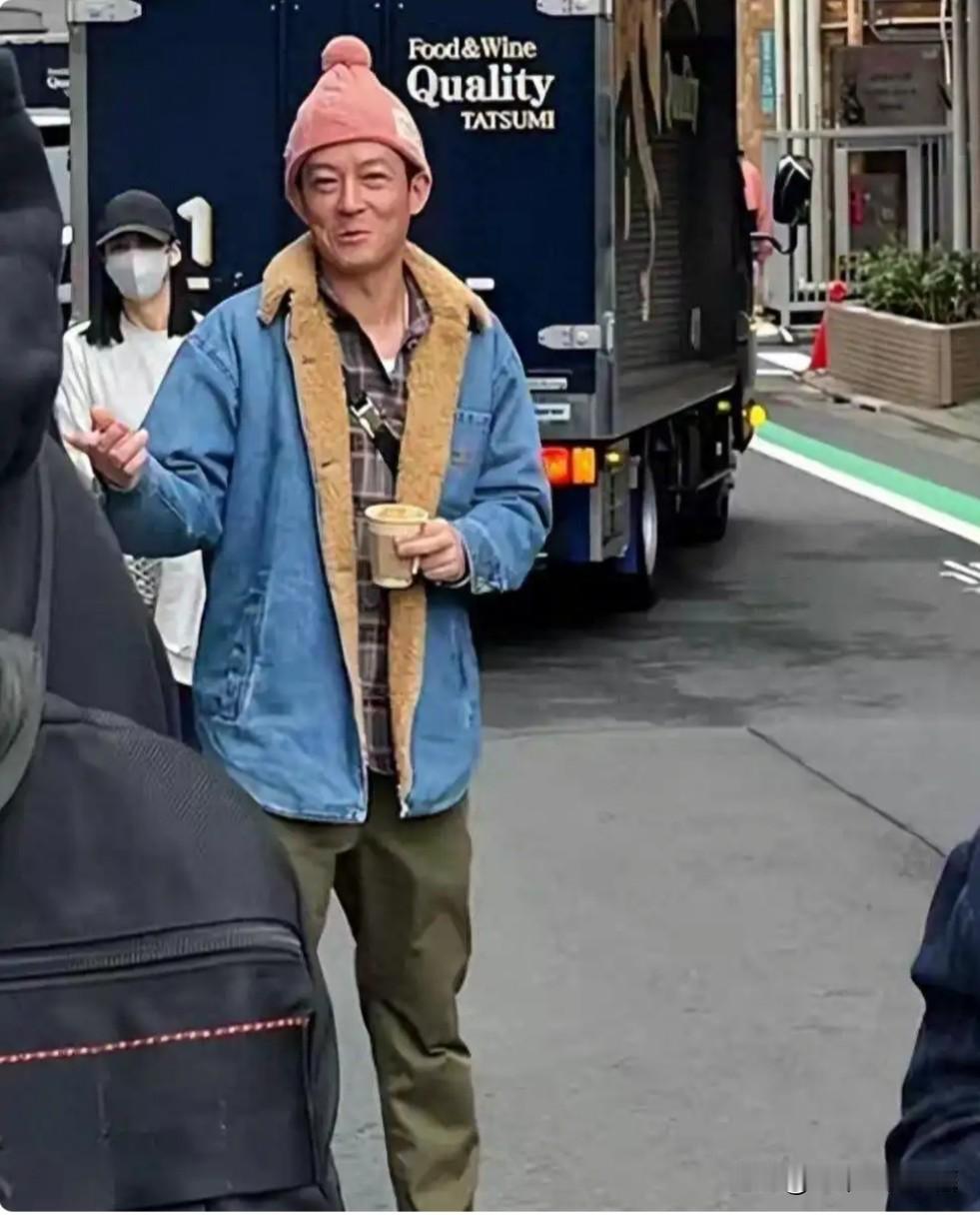 美国街头的陈冠希这造型，俨然就是一流浪汉，他穿着破旧的衣服，头戴绒球帽，手里拿着