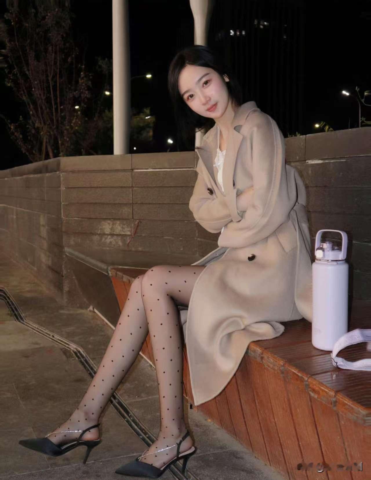 夜晚街头的优雅穿搭，米色风衣搭配黑高跟鞋，尽显都市女性魅力。