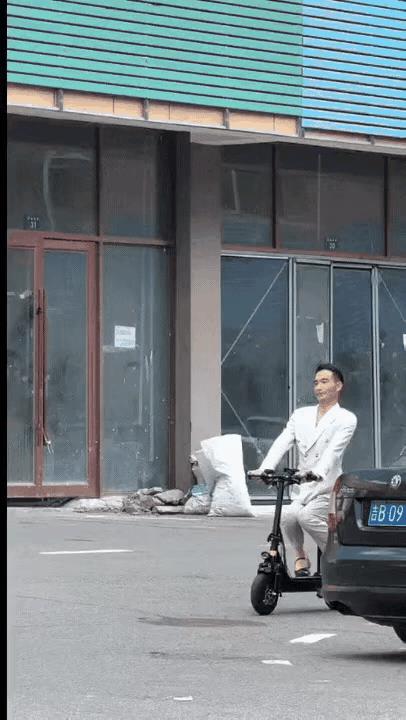 一个男人穿了一套白色的西服，脚上套了一双黄色的女袜子，脚下穿了一双黑色的女人拉带