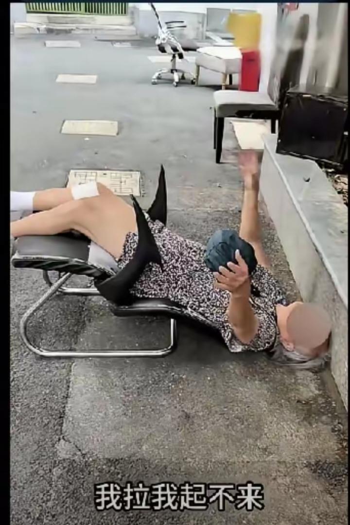远远看见老太太椅子后仰摔在地上，躺在地上动弹不得。两个年轻人不敢贸然上前搀扶，反
