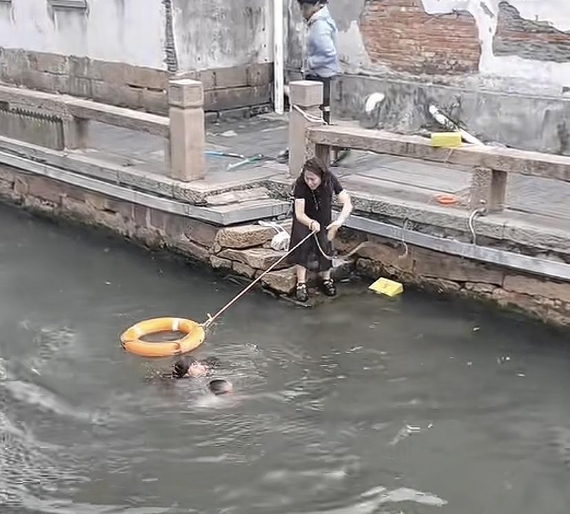 男孩落水，不会游泳的妈妈跳入水中，用尽全身力气把孩子往岸上推。6月6日苏州平江路