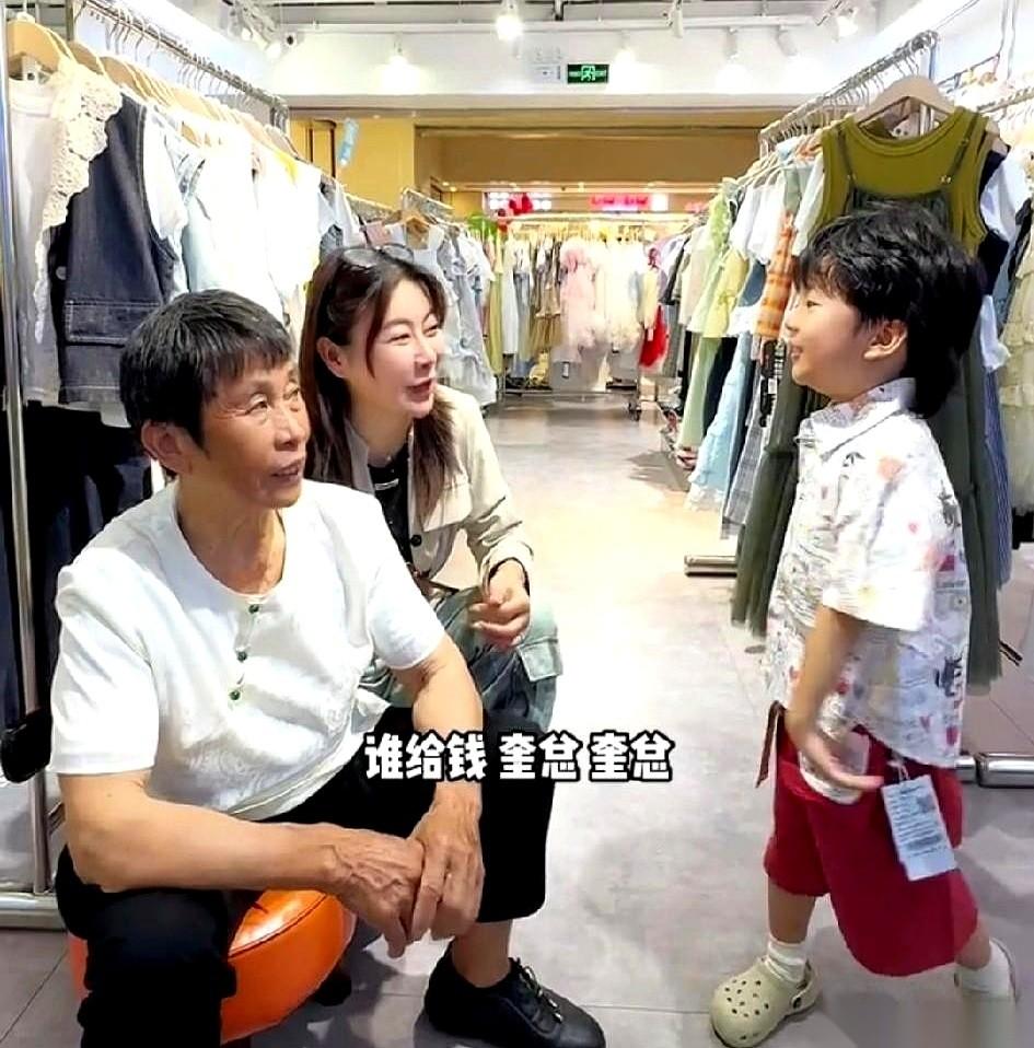 商场童装区，阿娟给小孙子挑好一件外套，笑着蹲下来问：“宝宝，谁给钱？”小孩没半