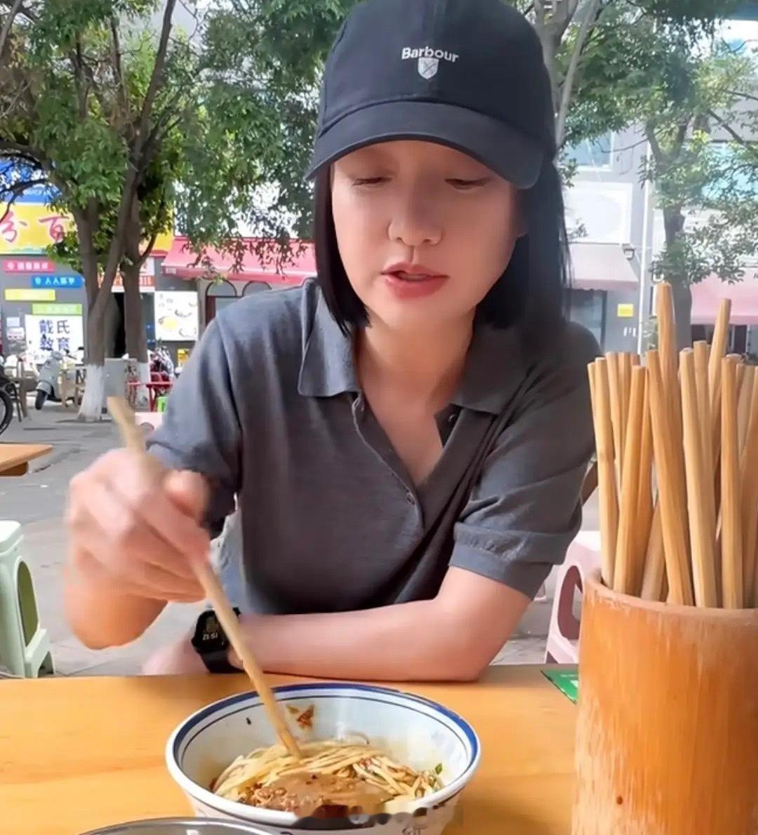 51岁周迅剪短头发了，她打扮低调坐在路边小桌上吃猪肝拌面，周围没有人认出来，状态