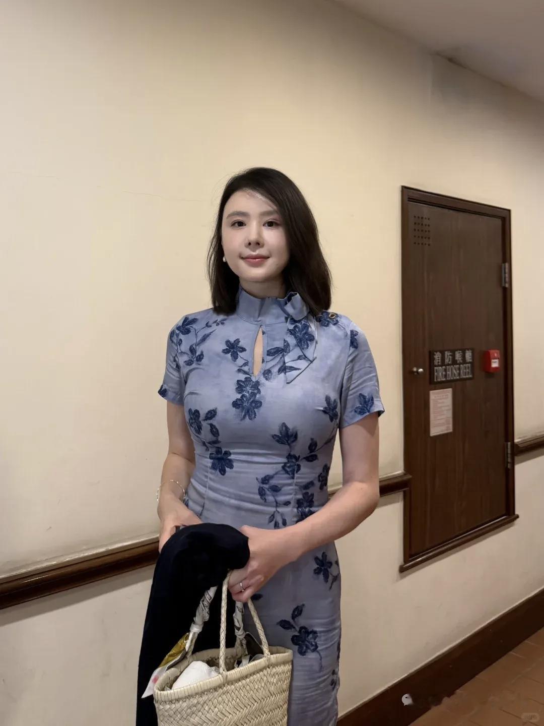 这位小姐姐穿着花旗袍，手拿外套和篮子。