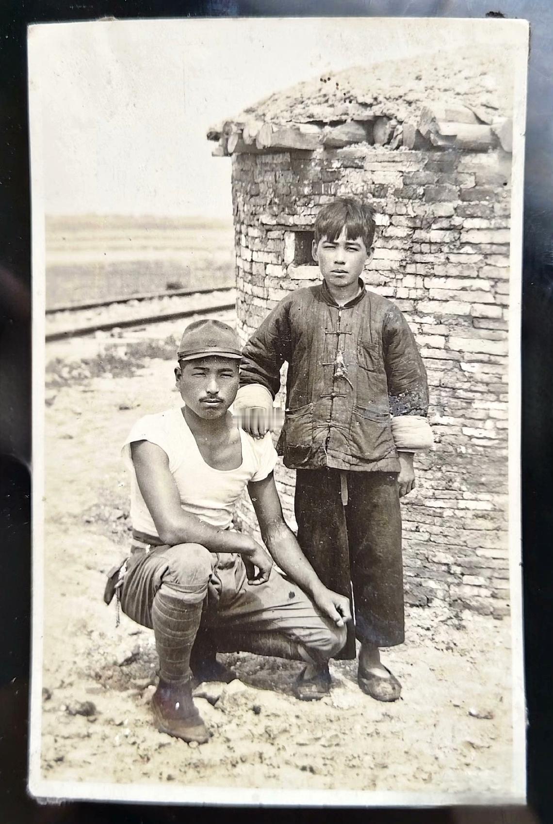 这是从日军随身携带的挂包搜出来的一张照片。在一座日军修建的碉堡面前，一名中国少年