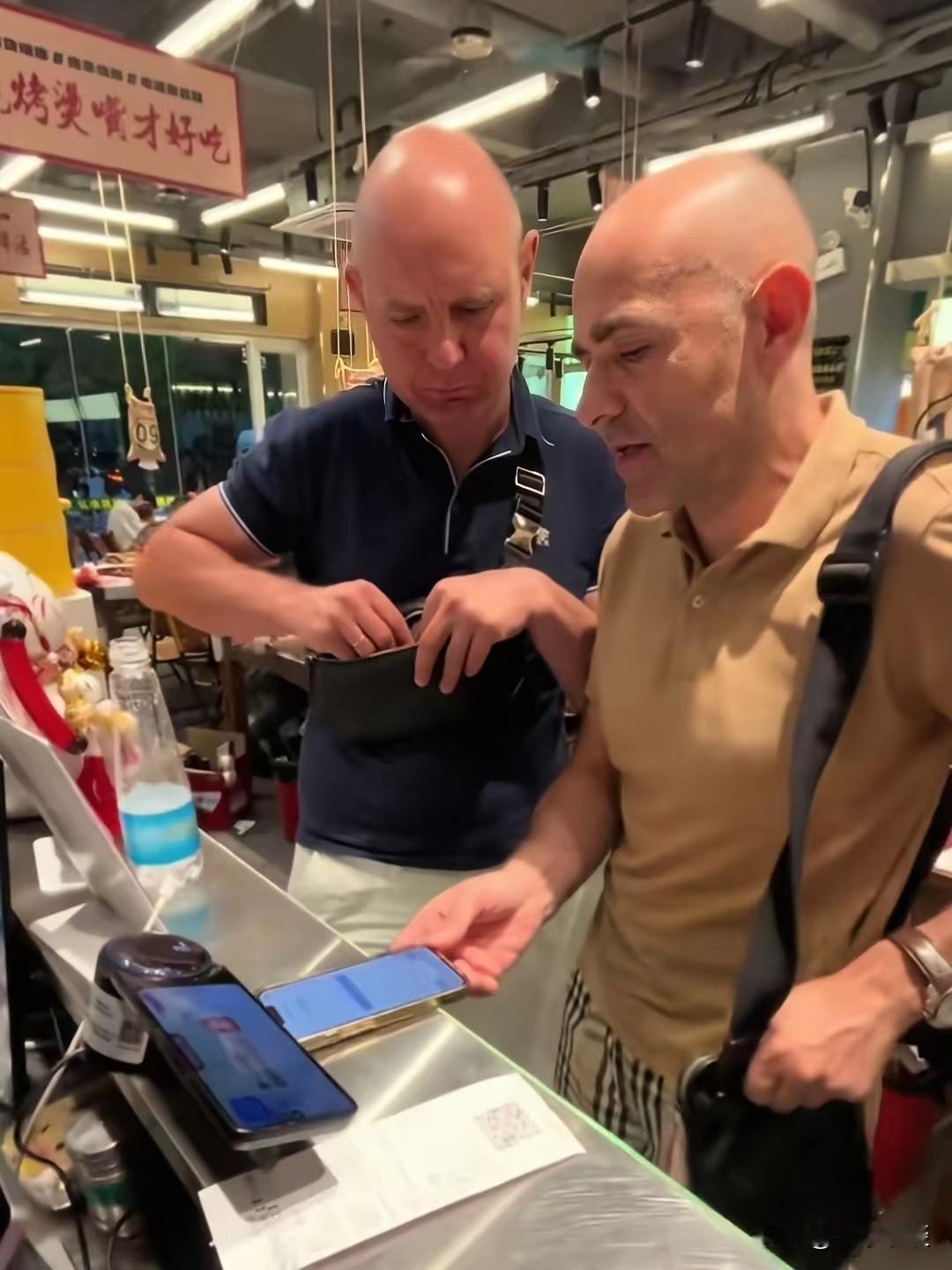 这两个老外在南昌吃烧烤，在前台结账时发现手机无法扫码支付，也没有现金人民币，老板